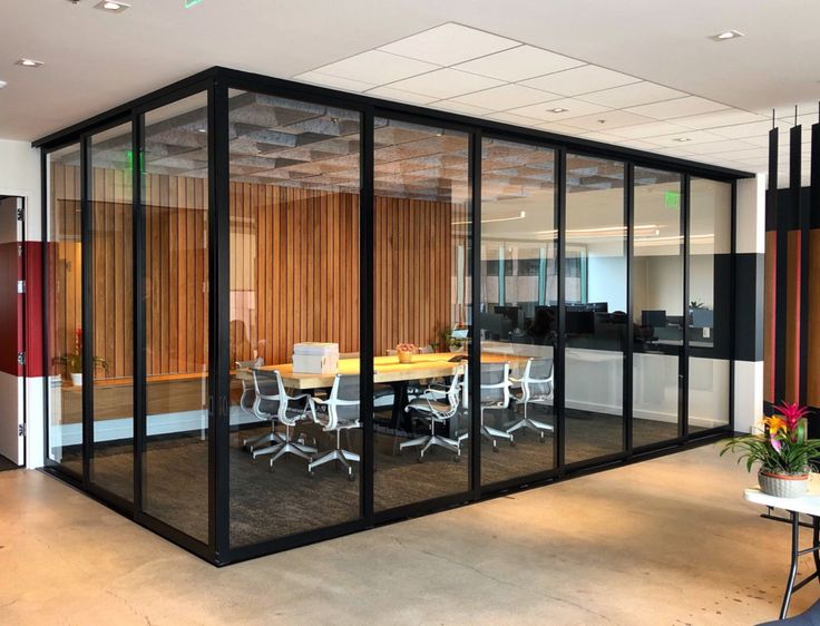 an office interior featuring full glass partitions with black aluminum frames