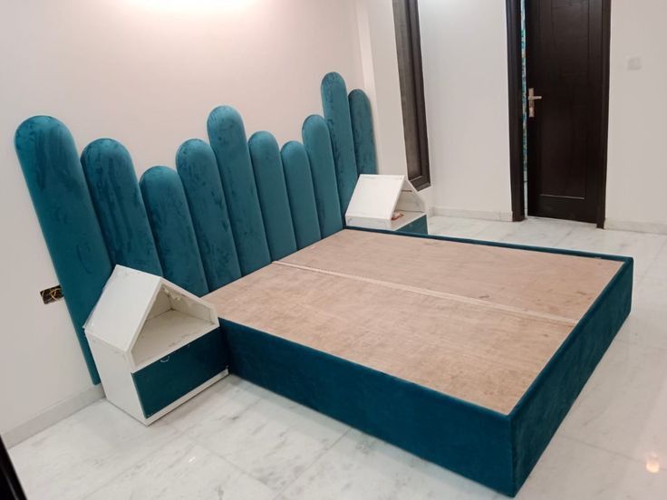 a king size designer wooden double bed with a unique teal upholstered headboard.